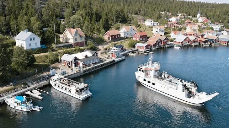 Färjan m/f Ulvön är på väg att angöra Ulvöhamn. Vid kajen ligger redan fartyget Minerva. 